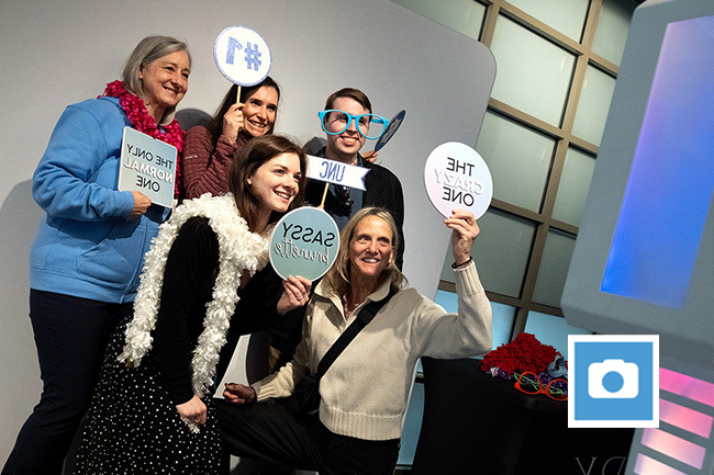 Carolina employees pose with signs at photo booth