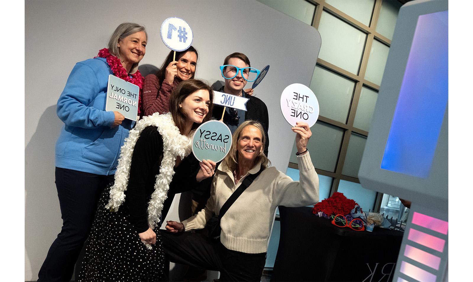 Carolina employees pose with signs at photo booth