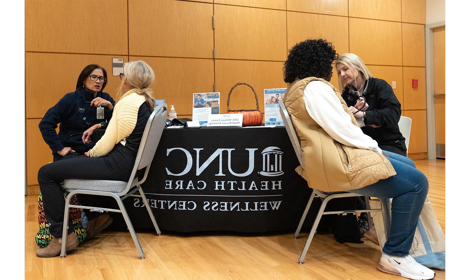 Carolina employees receive flu shots at table with UNC Health Care banner