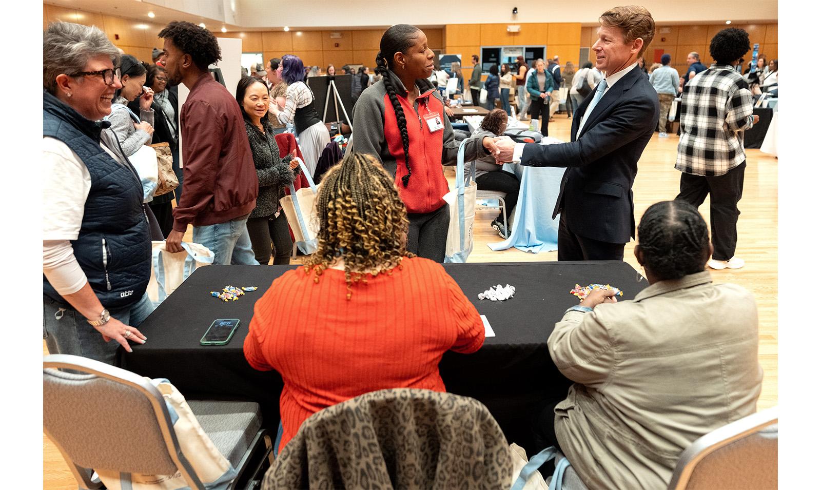 Chancellor Lee H. Roberts shakes an employee's hand in front of a table at Employee Appreciation Day