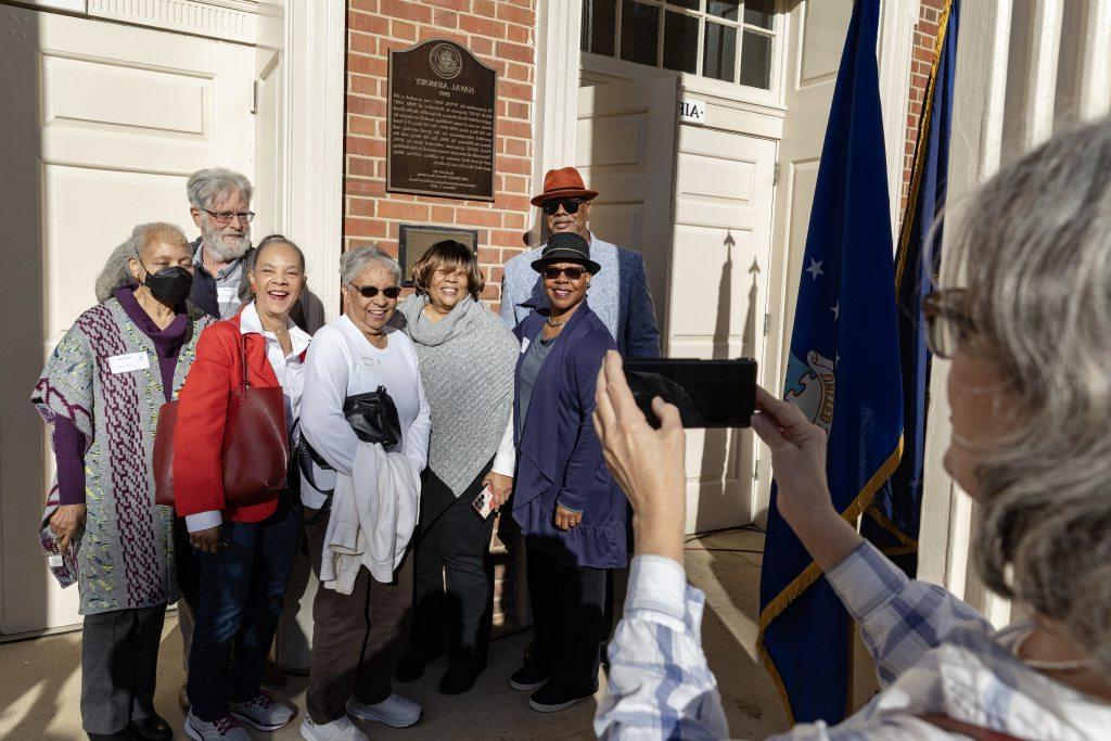 Descendants and friends of the original B-1 US Navy Band members posing for a group photo next to the historic marker outside the Naval ROTC Armory on the campus of UNC-Chapel Hill.